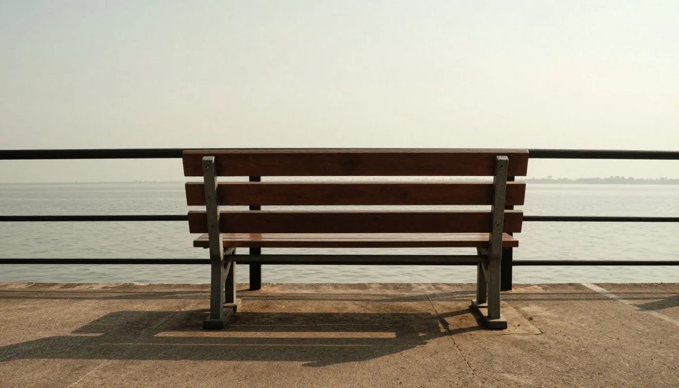 Quay rail and empty bench at four in the afternoon in Surabaya, warm hazy light over open water